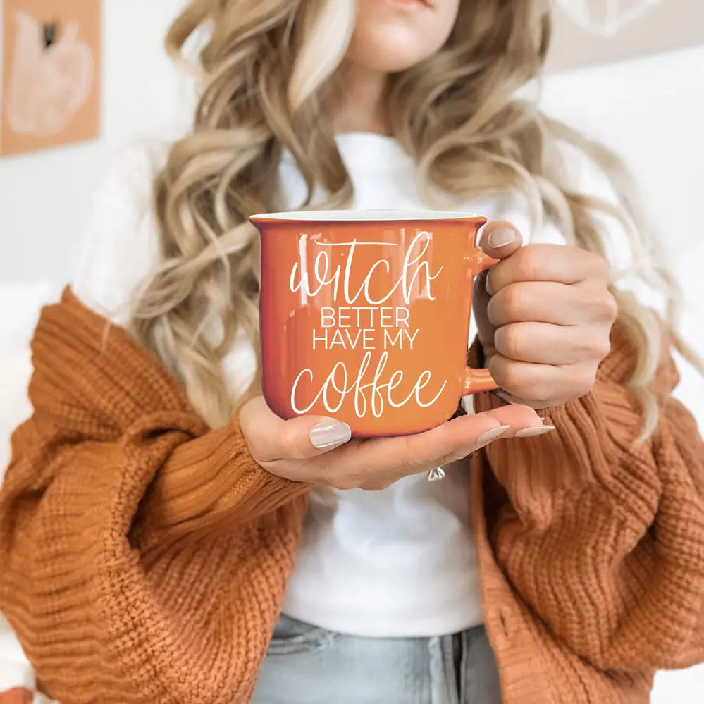 Person holding a mug with 'Dutch better have my coffee' text, wearing a brown sweater.