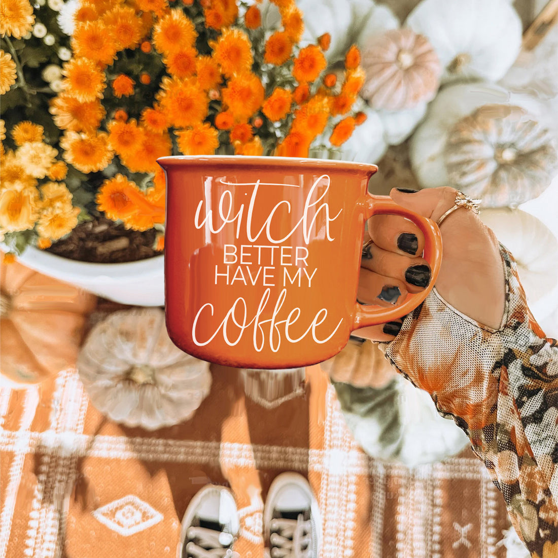Orange mug with 'Better Have My Coffee' text held by a hand, surrounded by autumn decorations.