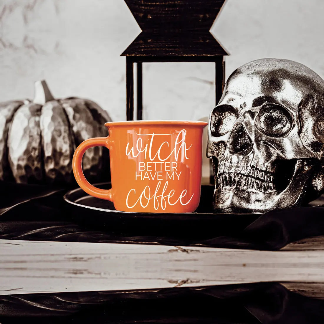 Orange mug with 'Witch better have my coffee' text, silver skull, and pumpkin on a wooden surface.