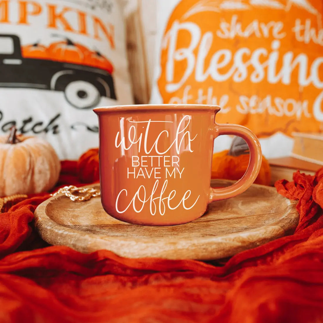 Orange mug with 'Ditch Better Have My Coffee' text on a wooden coaster with pumpkins and fall-themed decor in the background.