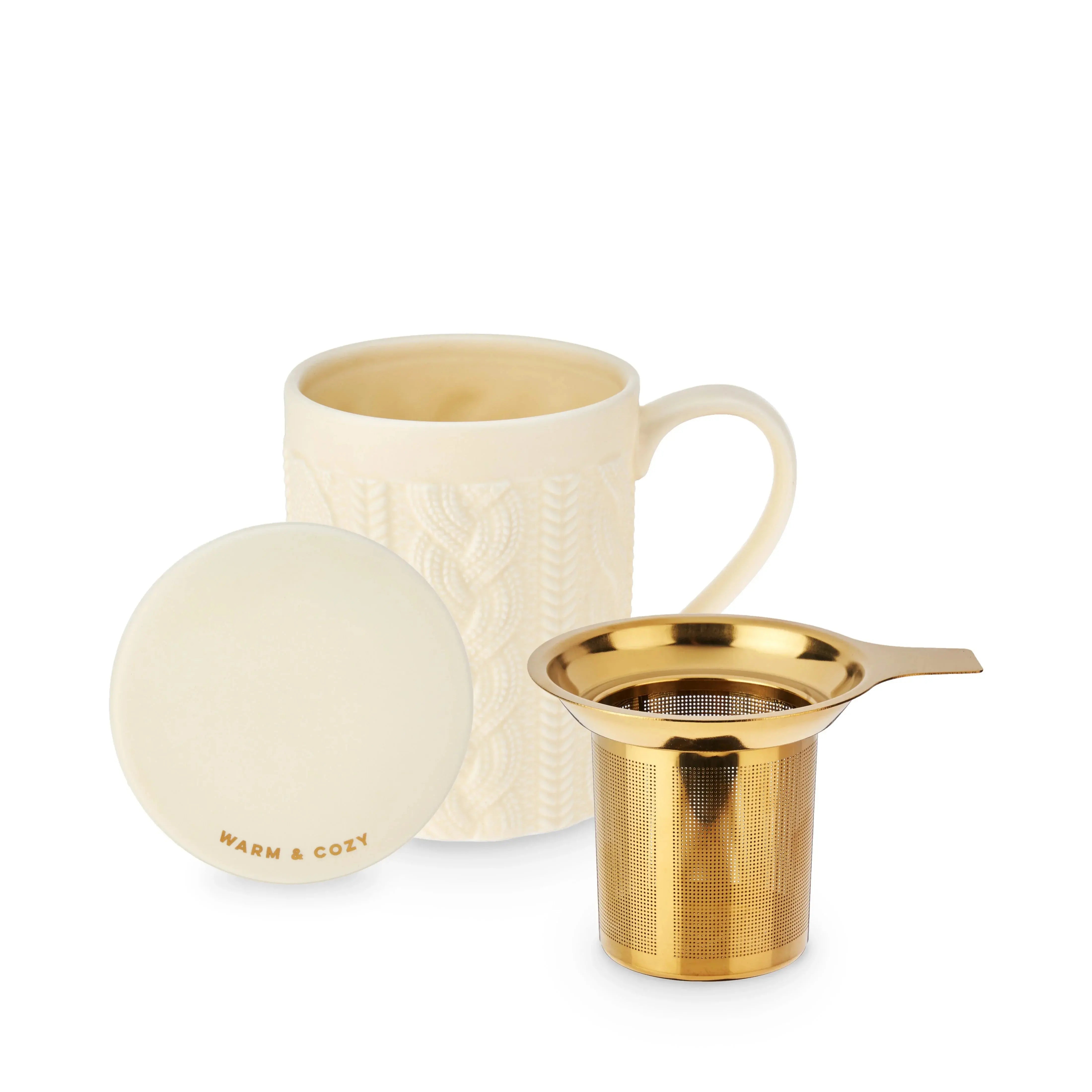 Cream-colored mug with gold mesh tea infuser and round white coaster on a white background